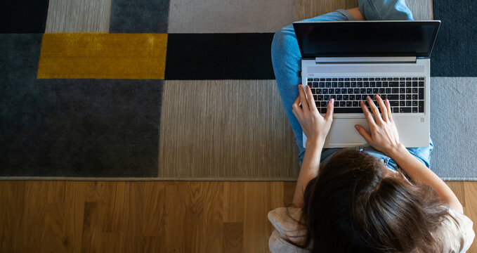 Banner View From Above Of Woman Working On A Laptop While Sitting On The Floor.