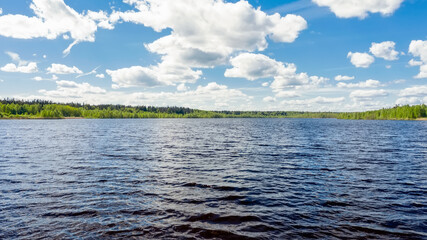 Top view of a blue long lake with green forests along the coast in Russia. Beautiful summer landscape.