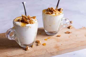 Cups of yogurt with honey and nuts on white background