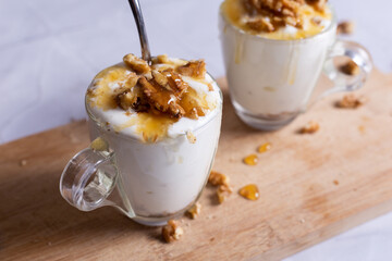 Cups of yogurt with honey and nuts on white background