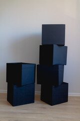 Black boxes in the shape of a cube on the background of an old wall