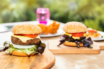 Close-up photo of home made Two large pieces of homemade hamburger pork, stacked with layers of delicious organic vegetables, placed on a wooden chopping board ready to eat.