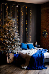 Elegant decorated Christmas tree with boxes of gifts in the interior near the bed