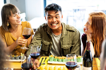 Happy friends eating and drinking at sushi restaurant - Food and beverage concept with young people having fun together at fusion bar - Vivid backlight filter