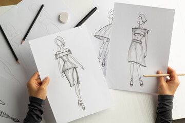 The designer draws sketches of women's dresses on paper.