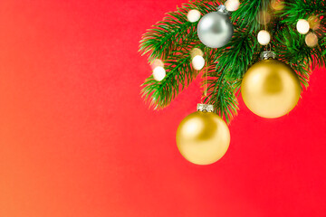 spruce branch with christmas ornaments and defocused lights on red background