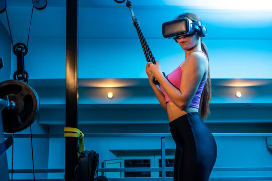 Attractive young red hair sportswoman training triceprs in the gym of her beautiful house with vr futuristic goggles. Ginger athletic model doing home sport pilates workout exercises during quarantine