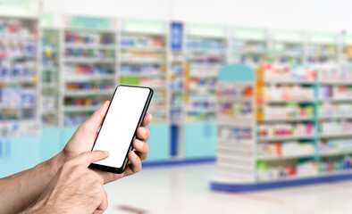 Pharmacy background. Blur counters of pharmacy with medicines, tablets, pills and hand with smartphone