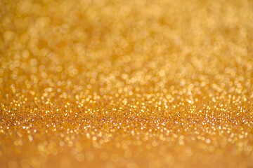 Glitter gold background. Texture foil and confetti bokeh, light of golden dust. Festive party Christmas and new year's eve background.