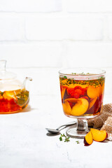 flavored black tea with fresh plums, berries and thyme on white background, vertical