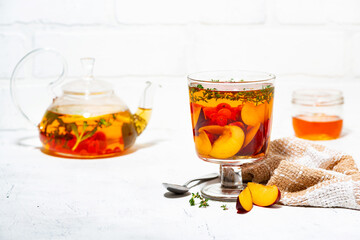 flavored black tea with fresh plums, berries and thyme on white background