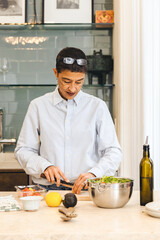 Mature adult woman prepares a salad in her kitchen