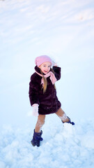 Fototapeta na wymiar A little girl on a winter walk throwing snowballs