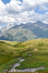 Summer mountain landscape in Svaneti region, Georgia, Asia. Snowcapped mountains in the background. Blue sky with clouds above. Georgian travel destination
