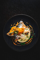 Fillet of mackerel with mashed potatoes and celery on dark background