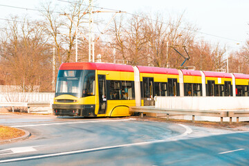 Yellow and red tram on the city street at autumn. Leafs. Fall. Trees. Outdoor. Transportation. Long. Sustainable. Public transport. Urban. Eco - obrazy, fototapety, plakaty