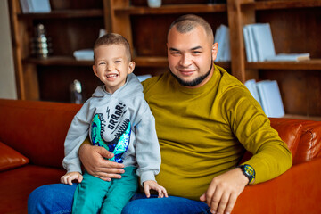 Portrait of adorable father and son sitting on the sofa at home