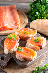 Slices of fresh baguette with butter and salmon served on wooden board