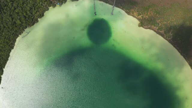 Aerial birds eye overhead top down panning view of beautiful green lake used as natural swimming pool. Kaan Luum lagoon, Tulum, Yucatan, Mexico