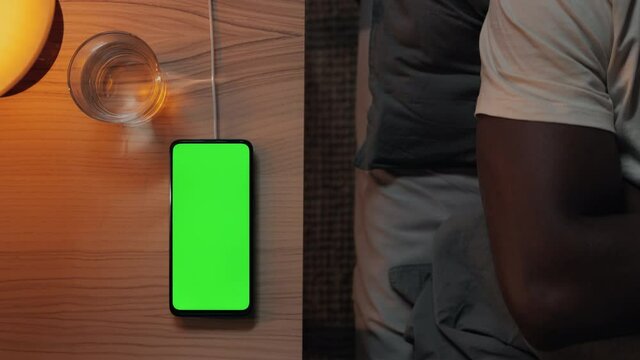 Man lying in bed and touching green mobile screen
