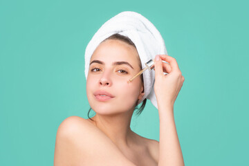 Attractive lady moisturizing face with oil. Beautiful girl with a towel on head, facial treatment, cosmetology, beauty and spa.