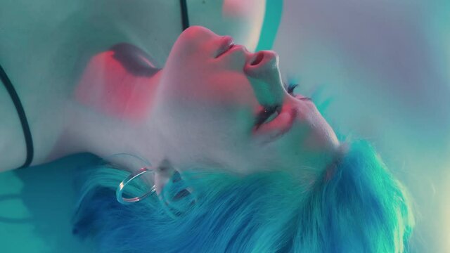 Neon woman face. Beauty care. Plastic surgery. Aesthetic cosmetology. Closeup of gorgeous model with flawless radiant skin in LED light blue red glow background.