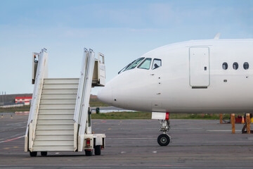 Fototapeta na wymiar Air-stairs near the passenger jet plane on the airport apron