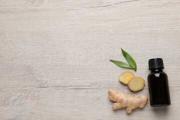 Glass bottle of essential oil and ginger root on white wooden table, flat lay. Space for text