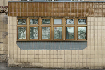 The entrance group to the old Soviet building of the 1980s, lined with beige ceramic tiles and with a wide window with gold frame made of anodized aluminum. Building of the Institute of Endocrinology.