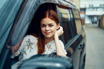 Obraz na płótnie Canvas cheerful woman driving a car looks out of the window