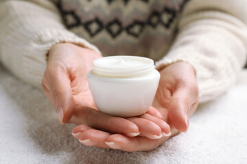 Woman with jar of hand cream over snow, closeup