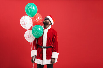 Black man in Santa suit smiling and posing with balloons