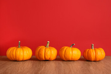 Fresh ripe pumpkins on wooden table against red background, space for text