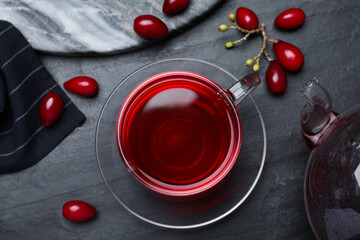 Naklejka na ściany i meble Glass cup of fresh dogwood tea and berries on black table, flat lay
