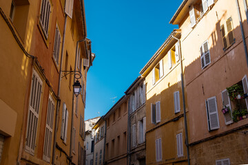 Colorful and beautiful small alley in the old town of the french city of Aix en Provence on a summer day with clear blue sky and traditional houses and architecture