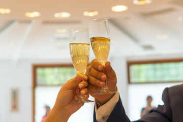 Hands of the groom and bride with rings toasting with glasses of champagne at a wedding celebration