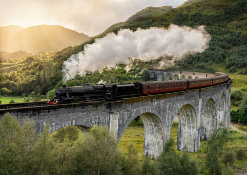 Steam train crossing the Glenfinnan viaduct in the Scottish Highlands made famous by the Harry Potter movie as Hogwarts Express,, Jacobite steam train crossing the bridge in Scotland United Kingdom