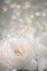 Silk white flowers roses with lace and blurred light background with beautiful yellow bokeh. Christmas decoration. Soft focus