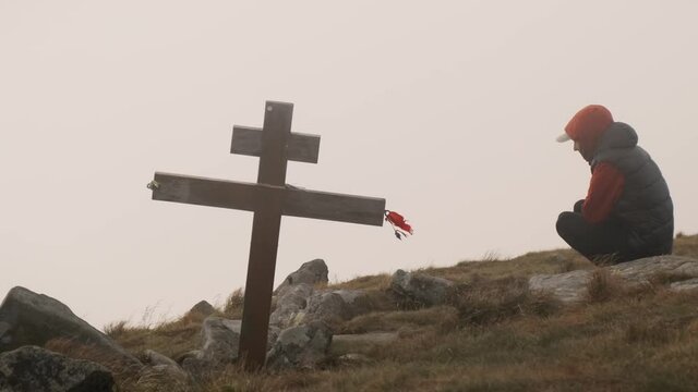 Loss of loved ones concept. Unrecognizable man in depression near grave with cross praying for death of loved one. Sad man near cross mourns deceased. Frustrated human feels lonely depression sufferin