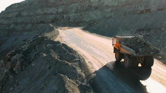 Career dump truck goes in a gold mine. Aerial view of large mining trucks on a gold mine. Open pit mine quarrying extractive industry stripping work.