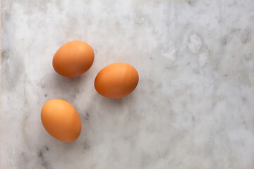 Top view of three raw brown egg with copy space on marble surface