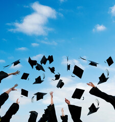 Graduating students hands throwing graduation caps in the air