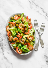 Delicious appetizers salad with shrimp, crispy iceberg, crackers and olives on a light background, top view
