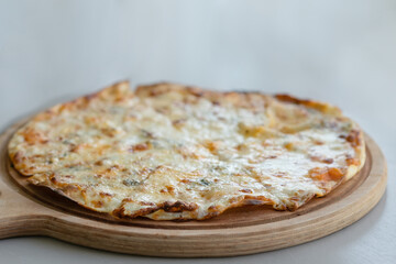 A four cheeses domestic crunchy pizza on a wooden plate
