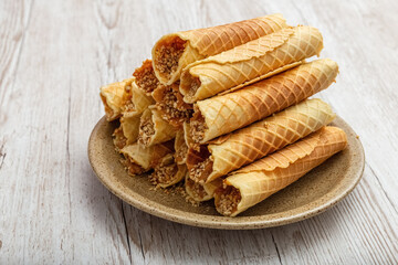 Wafer rolls with cream on a plate. Delicious dessert. Homemade. Wooden background. Photo