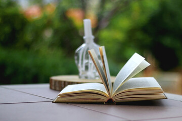 Open book and candle in a garden. Selective focus.