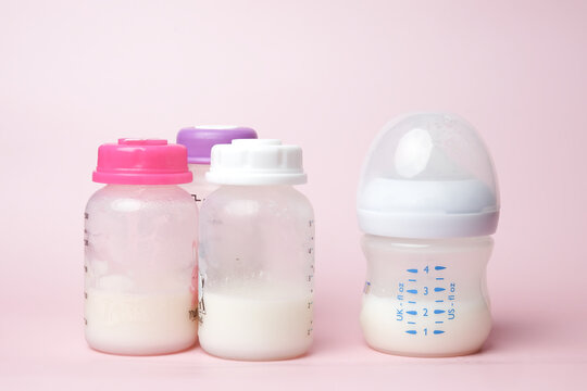 A picture of drink and three storage baby bottle on pink background. Breast milk is good source of calcium and protein for baby.