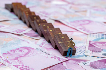 Turkish lira money, cash money with dominoes and magnifying glass. Miniature people standing on...