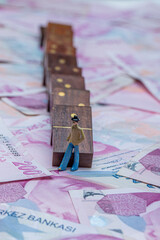 Turkish lira money, cash money with dominoes and magnifying glass. Miniature people standing on domino cubes with stacks of money. Saving money, finance, business, goal achievement concept.
