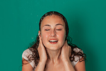 Beautiful young girl under shower drops, portrait on a green background